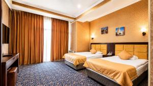 a hotel room with two beds and a television at Ruma Qala Hotel in Sheki