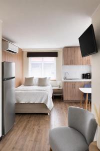 a bedroom with a large bed and a kitchen at Studios y Departamentos Nómades del Lago in Puerto Varas