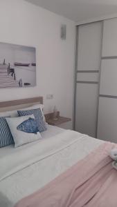 a white bed with blue and white pillows on it at Areos de Cabío in A Pobra do Caramiñal