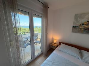 a bedroom with a bed and a view of a balcony at Apartman with sea view KAVALA- Pašman, Kraj in Kraj