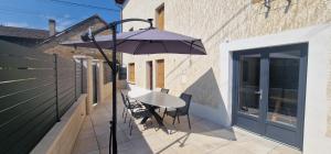 a patio with an umbrella and a table and chairs at La maison de Morgane in Tourmont