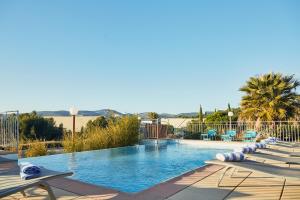 a large swimming pool with lounge chairs and palm trees at ibis La Ciotat in La Ciotat