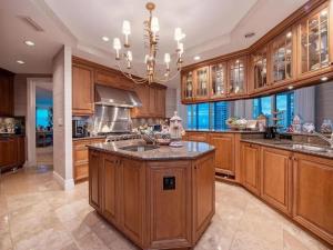 a large kitchen with wooden cabinets and a chandelier at Beachfront Elegance Escape in Naples +24 photos