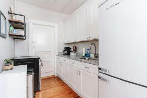 a white kitchen with white cabinets and a refrigerator at Oglethorpe Square Historic Apt Central & Walkable in Savannah