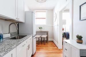 a kitchen with white cabinets and a sink and a table at Oglethorpe Square Historic Apt Central & Walkable in Savannah