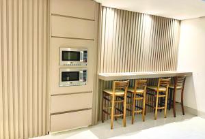 a bar with a row of stools and a microwave at Hotel Arujá in Arujá