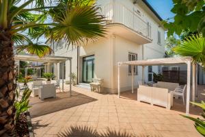 a patio of a house with white furniture and palm trees at Hotel La Perla in Marina di Massa