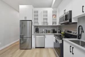 a kitchen with white cabinets and a stainless steel refrigerator at Rare 3BR Gem Mini Putt Terrace & CN Tower Views in Toronto
