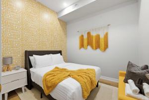 a bedroom with a bed with a yellow blanket on it at Rare 3BR Gem Mini Putt Terrace & CN Tower Views in Toronto
