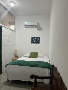 a white bedroom with a bed with a green blanket at Lu House in Flores