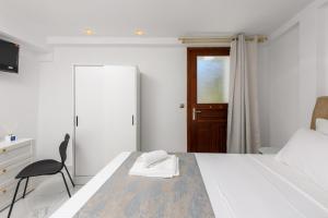 a bedroom with a bed and a chair and a door at Villa Andriana in Panagia