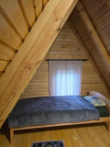 a bed in a wooden room with a window at Forest soul "Jaslice" - Ozren in Doboj +13 photos