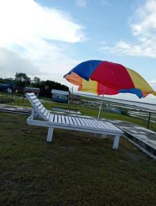 a bench with a colorful umbrella sitting on the grass at Bonolota Eco Villa in Mongla
