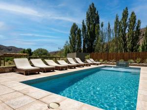 a pool with chaise lounge chairs and a swimming pool at Posada del Blanco in Potrerillos