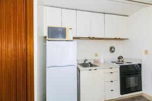 a white kitchen with a microwave on top of a refrigerator at Ilikai Marina 1495 in Honolulu