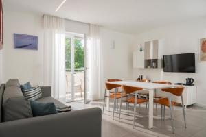 a white living room with a table and chairs at Hotel Daniele in Lignano Sabbiadoro