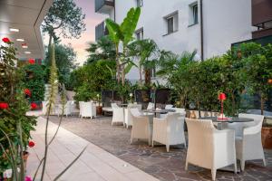 a restaurant with white chairs and tables and plants at Hotel Daniele in Lignano Sabbiadoro