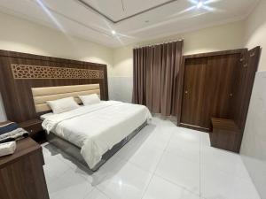 a bedroom with a large bed and a wooden headboard at كيان التيسير - حي التيسير in Jeddah