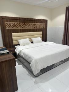 a bedroom with a large bed with a wooden headboard at كيان التيسير - حي التيسير in Jeddah