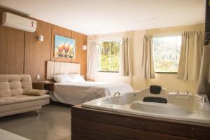 a hotel room with a tub and a bed at Vale Das Araras Nas Videiras in Araras Petropolis +202 photos