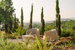 two chairs in a garden with cypress trees at Vila das Acácias - Boutique Villa in Wine Country in Alenquer