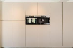 a wall of white cabinets with a microwave at Vila das Acácias - Boutique Villa in Wine Country in Alenquer