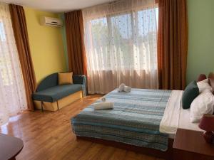 a bedroom with a bed and a chair and a window at Свети Кирил Лозенец in Lozenets