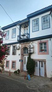 a white house with a balcony on the side of it at Mimosa House Ayvalık in Ayvalık