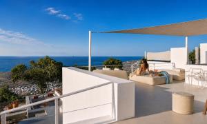 a woman sitting on the balcony of a house at Santorini Heights in Pyrgos