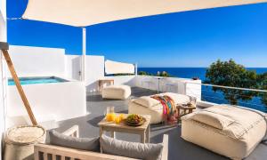 a patio with white furniture and an umbrella at Santorini Heights in Pyrgos