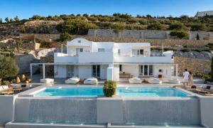 a villa with a swimming pool in front of a house at Santorini Heights in Pyrgos