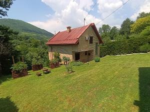 a house with a red roof on a grass field at Holiday Home Zbilje in Visoko