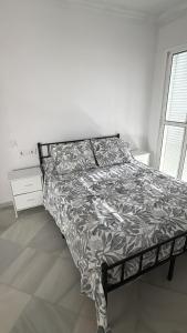 a bed in a white room with a bedspread on it at Apartamentos Lebrero in San Fernando