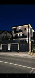 a large white building with lights on the side of a street at Apartmani Sjenjak Prestige in Tuzla