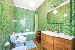 a bathroom with a sink and a toilet and green tiles at Villa I Tre Archi for 6 with Private Garden - Happy Rentals in Pisano +25 photos