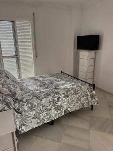a bedroom with a bed and a dresser and a television at Apartamentos Lebrero in San Fernando