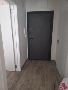 a hallway with a black door and a wooden floor at Рока Резиденс in Ravda