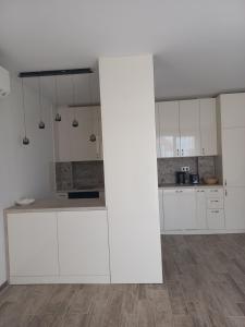 a white kitchen with white cabinets and a wooden floor at Рока Резиденс in Ravda