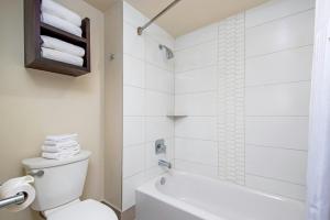a bathroom with a tub and a toilet and a shower at Peacock Suites in Anaheim