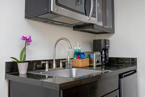 a kitchen counter with a sink and a microwave at Peacock Suites in Anaheim +41 photos
