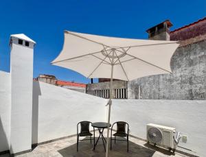 a table and two chairs under a white umbrella at Ducal Guest House in Vila Viçosa