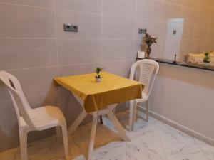 a table with two chairs and a yellow table cloth on it at Relax House 2 in Al Massira Airport +10 photos