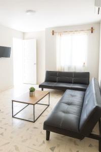 a living room with a black leather couch and a coffee table at Villa Bonita Torre 11 3 in Cozumel