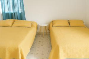 two beds in a room with yellow sheets and a table at Villa Bonita Torre 11 3 in Cozumel