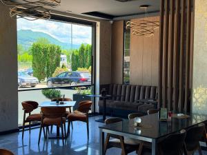 a restaurant with tables and chairs and a large window at Prenoćište BIS in Prijepolje