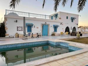 a house with a swimming pool in front of a house at La maison des oliviers in Houmt Souk