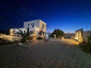 a large white building with a courtyard at night at La maison des oliviers in Houmt Souk