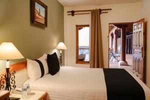 a bedroom with a large white bed and a doorway at Hotel la Parroquia in Pátzcuaro