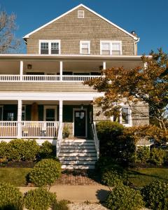 a large white house with a porch and stairs at The Bentley Inn in Bay Head