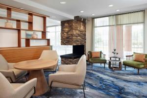a waiting room with a table and chairs and a fireplace at Fairfield Inn & Suites by Marriott Stafford Quantico in Stafford